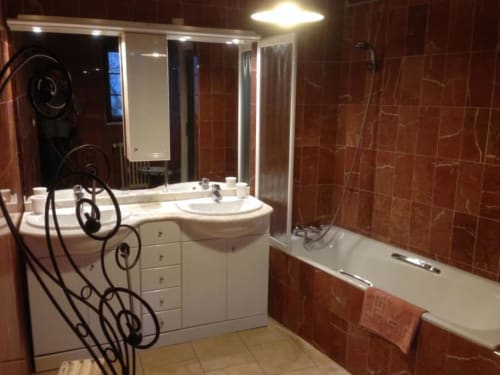 Salle de bain moderne au Moulin De La Côte avec carrelage en terre cuite, vasque blanche, miroir éclairé et baignoire avec douche