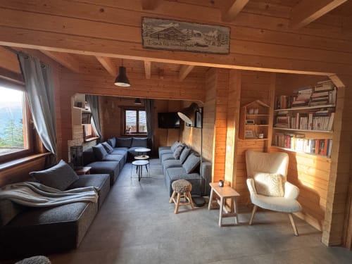 Spacieux salon de chalet en bois avec vue sur les montagnes, sièges confortables, bibliothèques et lumière naturelle au Chalet