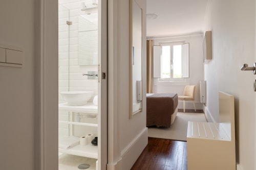 Quarto moderno do Oporto Comfort Charming com casa de banho privada, soalho de madeira, sala de estar e vista da cidade