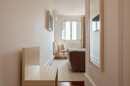 Quarto moderno do Oporto Comfort Charming no Porto com cama, área de estar, pisos de madeira e janelas com vista para a cidade