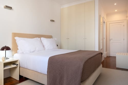 Quarto moderno no Oporto Comfort Charming Cedofeita no Porto com guarda-roupa bege, cama de madeira, roupa de cama branca e