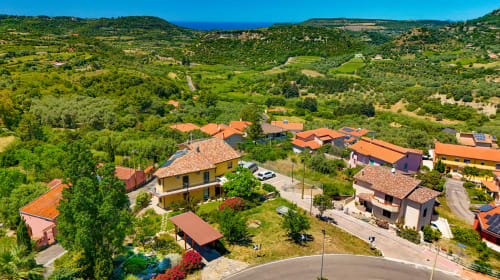 Complesso villa Sardegna Explora con edifici dai tetti arancioni immersi nelle lussureggianti colline sarde affacciate sulla costa
