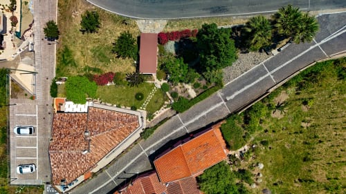 Vista aerea della villa Sardegna Explora House a Modolo con tetti in coppi rossi, giardini lussureggianti e palme