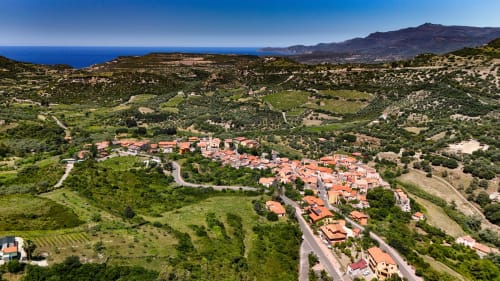 Villaggio di Modolo con tetti in terracotta immerso nella campagna sarda con mare e montagne sullo sfondo