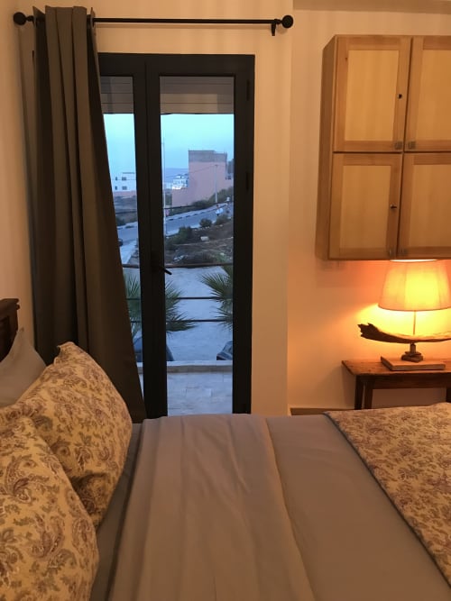 Bedroom with sea view at Imsouane Surf Paradise hotel, featuring bed, lamp, and balcony overlooking water