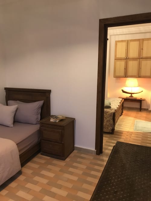 Tiguemi room at Imsouane Surf Paradise with wooden bed, nightstand, and doorway to sea-view suite in Agadir, Morocco