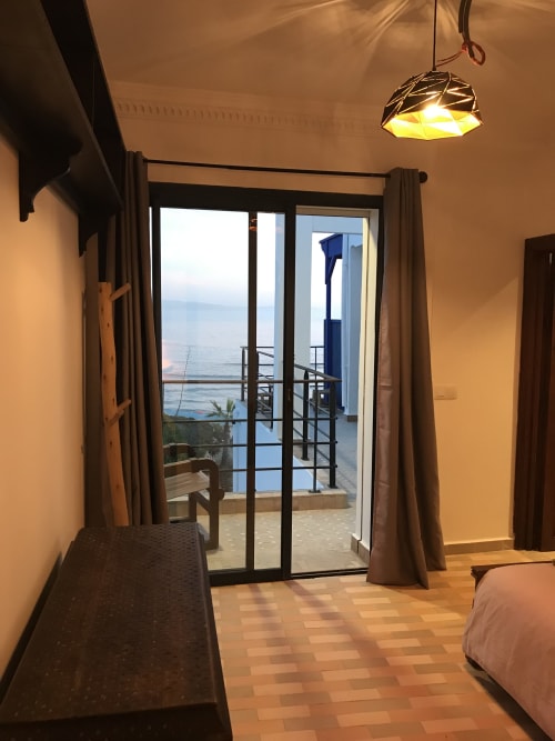 Tiguemi room at Imsouane Surf Paradise with sea view balcony overlooking ocean, terrace access, and warm lighting