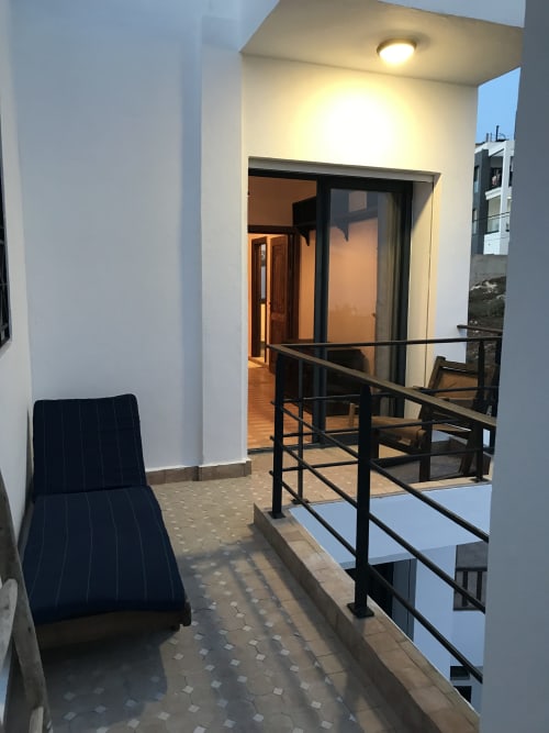 Imsouane Surf Paradise terrace entrance with sea view balcony, dark lounge chair, and modern railing in Agadir