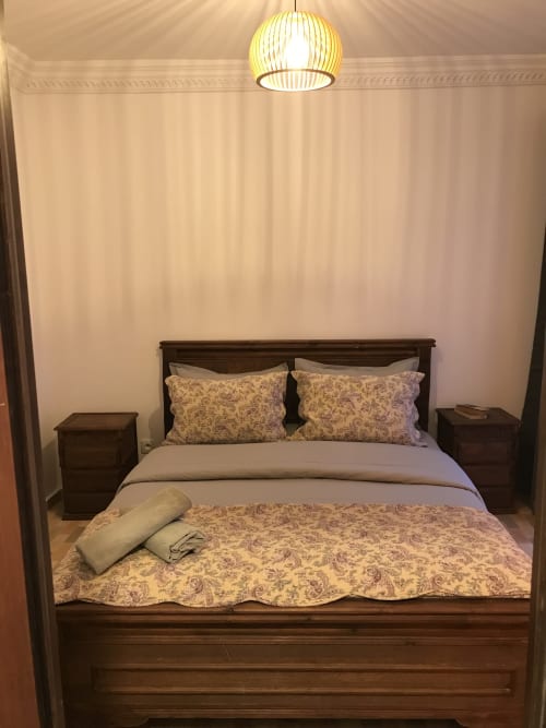 Cozy bedroom at Imsouane Surf Paradise hotel in Agadir, Morocco with dark wood bed, patterned pillows and pendant lamp