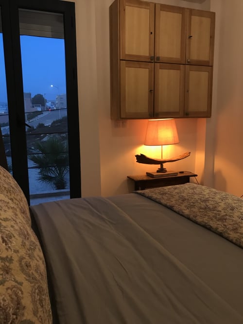 Tiguemi bedroom at Imsouane Surf Paradise with sea view, lit bedside lamp, wooden cabinets, and balcony overlooking Agadir