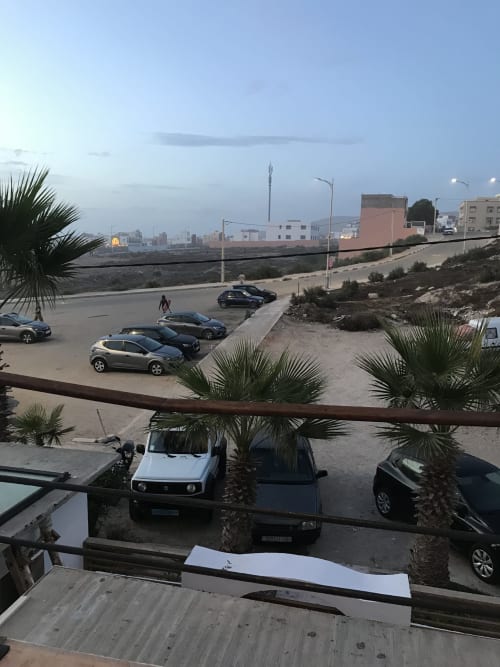 Parking lot and coastal cityscape view from Imsouane Surf Paradise hotel room balcony in Agadir, Morocco at dusk