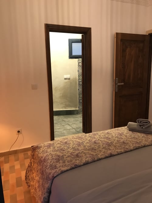 Tiguemi room at Imsouane Surf Paradise with bed, glass door to sea view balcony, and wooden doors