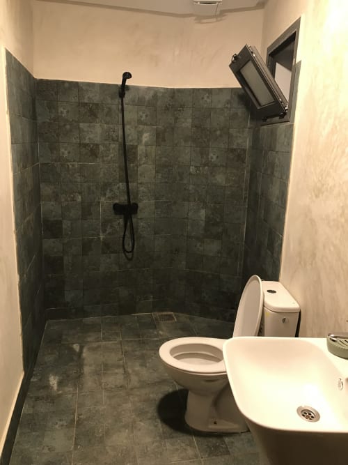 Modern bathroom with gray tile shower, white toilet and bidet at Imsouane Surf Paradise hotel in Agadir, Morocco