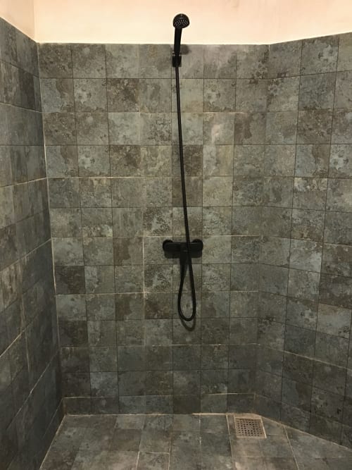 Modern tiled shower enclosure with black showerhead and handheld spray at Imsouane Surf Paradise, Agadir