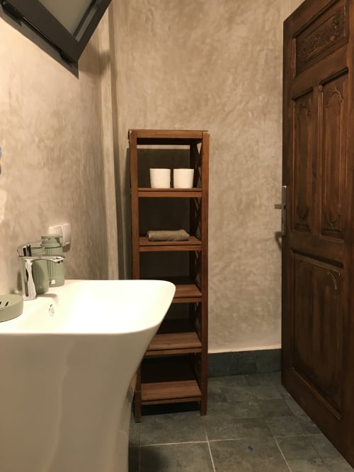 Modern bathroom at Imsouane Surf Paradise with white bathtub, wooden shelving, and dark tile flooring in Agadir, Morocco
