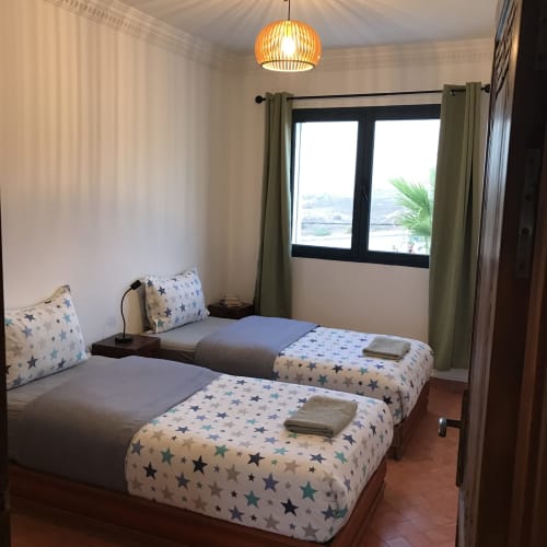 Twin bedroom with star-patterned bedding and sea view at Imsouane Surf Paradise hotel, Morocco