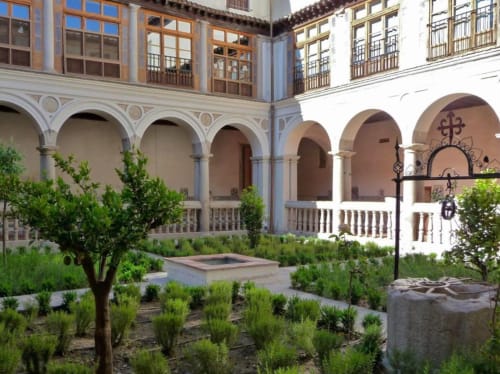 Patio Príncipe David en Toledo con columnata arqueada, jardines exuberantes y arquitectura española tradicional