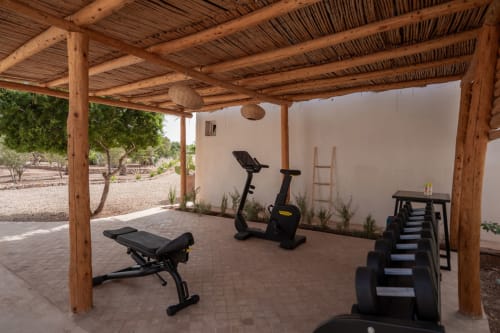 Pavillon de fitness en plein air au Domaine Belhazar à Essaouira avec vélos d'exercice, poids et bancs de musculation sous structure en bois