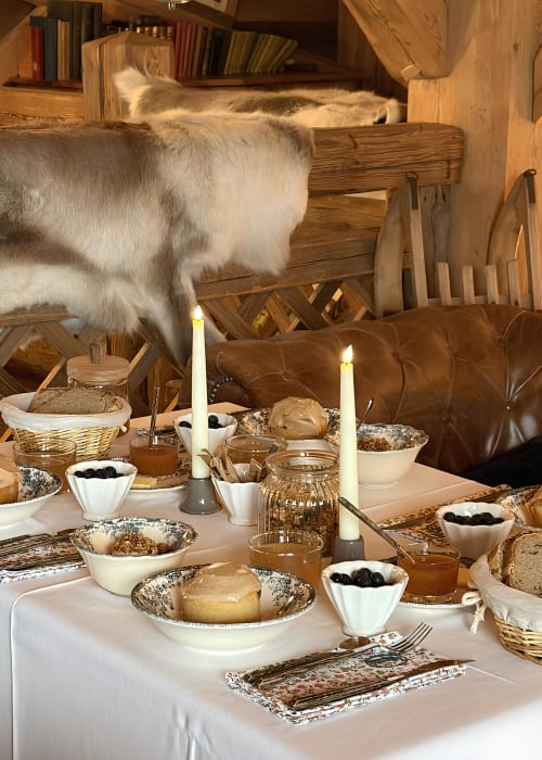Chèvre blanche sur table en bois rustique garnie de pain, olives et bougies à La Ferme 1828 B&B à Demi-Quartier