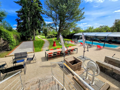 Außenbereich des Vindihouses B&B in Epinac mit überdachtem Pool, Sitzgelegenheiten, Picknicktisch, Feuerstelle und gepflegtem Garten.