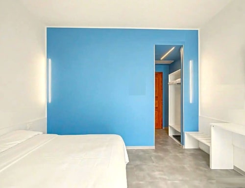 Modernes Schlafzimmer im Hotel Ca 'Tron in Dolo mit blauer Akzentwand, weißer Bettwäsche und minimalistischem Design