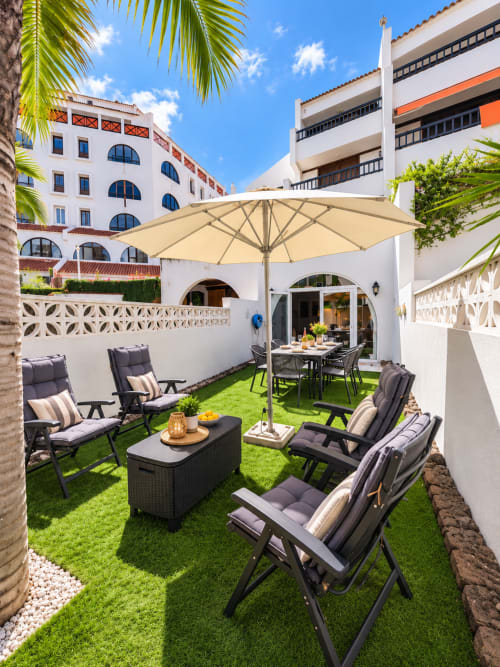 Elegant outdoor patio at Manage Home Tenerife in Playa de las Américas with lounge chairs, umbrella, and dining area