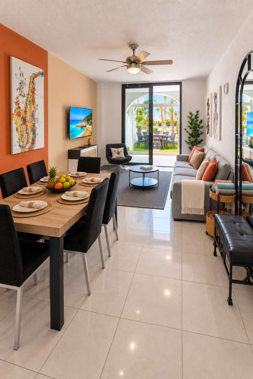 Modern open-plan living and dining area in Elegance Duplex apartment, Playa de las Américas, with orange accent wall, wooden