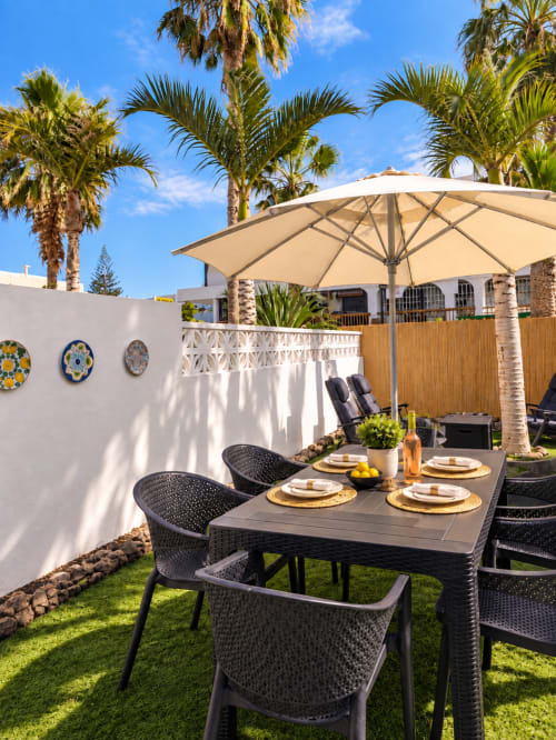 Elegant patio dining area at Manage Home Tenerife with palm trees, umbrella, and table setting in Playa de las Américas