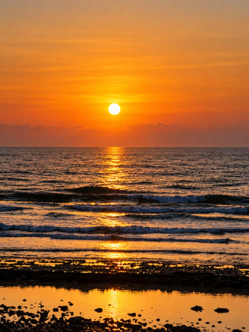 Golden sunset over Playa de las Américas beach with waves and rocky shore, Tenerife