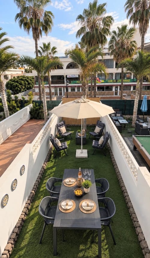Elegant courtyard at Manage Home Tenerife with dining table, lounge seating, umbrella, and palm trees in Playa de las