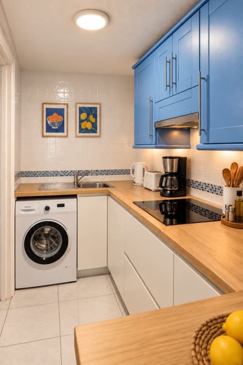 Modern kitchen in Elegance Duplex apartment, Tenerife, with blue cabinets, wooden counters, and stainless steel appliances