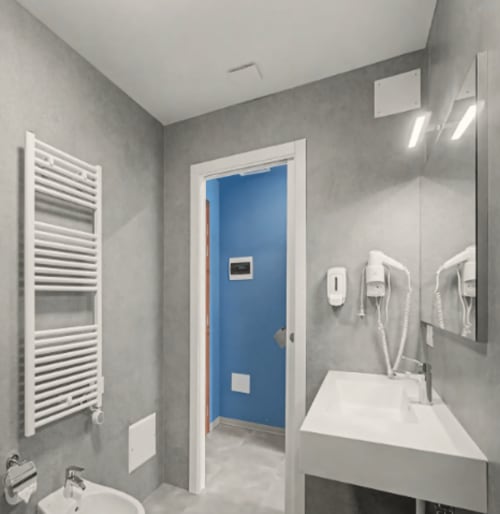 Bagno moderno dell'Hotel Ca 'Tron con pareti grigie, lavandino bianco, scaldasalviette e ingresso della doccia blu a Dolo