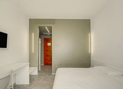 Camera d'hotel moderna a Ca'Tron con letti gemelli, design minimalista e porta rossa di accento a Dolo