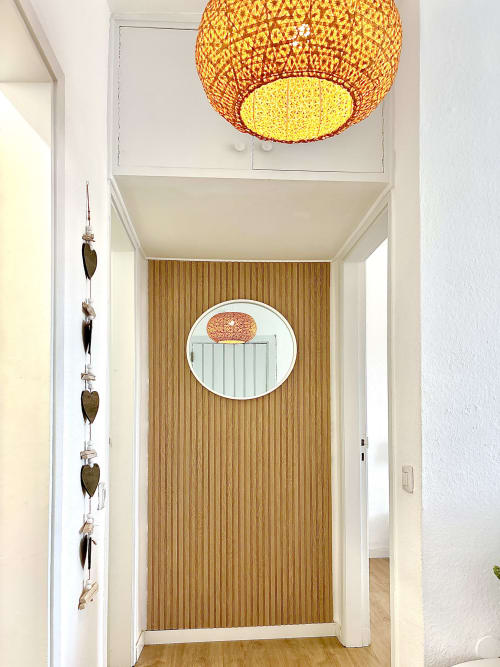 Modern hallway in Los Cristianos apartment with woven pendant light, wooden accent wall, and decorative mirror