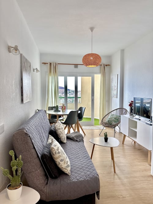 Modern apartment living room in Los Cristianos with sea view, sofa, dining area, and balcony access