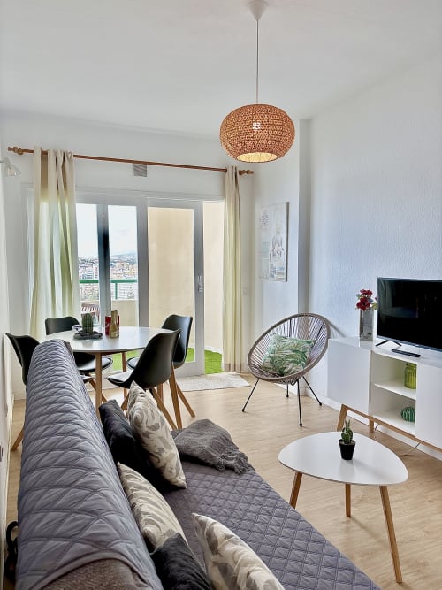 Modern apartment living room in Los Cristianos with sea view, dining area, woven pendant light, and TV at Manage Home
