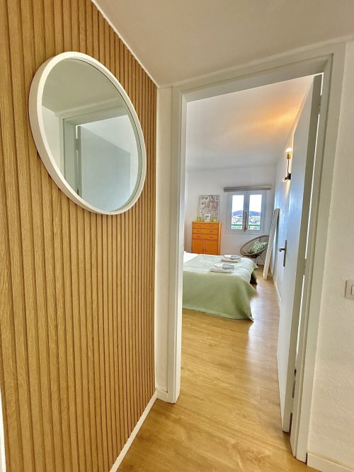 Hallway to sea view bedroom in Los Cristianos apartment with round mirror and wooden wall panels