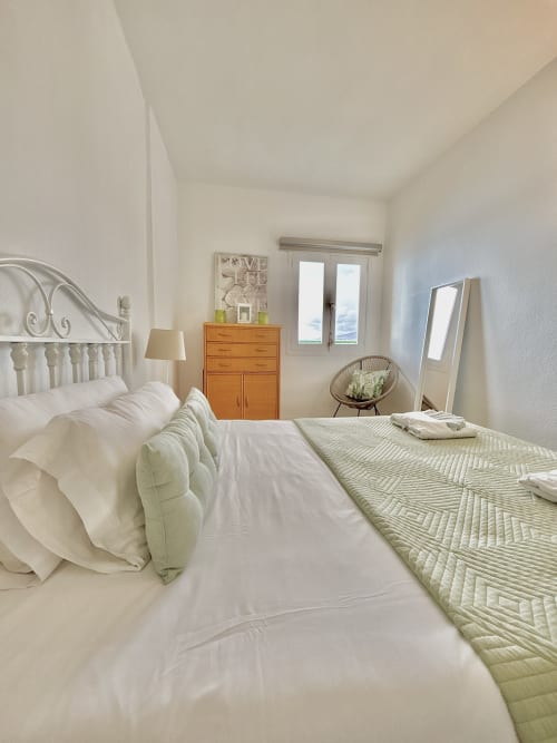 Bright bedroom at Manage Home Tenerife Los Cristianos with sea view, white iron bed, wooden dresser, and modern amenities