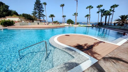 Crystal blue swimming pool with palm trees and sea view at Manage Home Tenerife, Los Cristianos