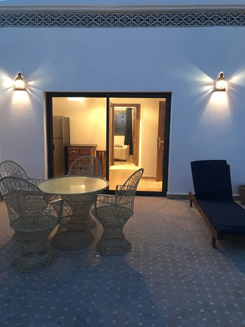 Imsouane Surf Paradise terrace at dusk with wicker seating and open glass doors to TASSILA apartment