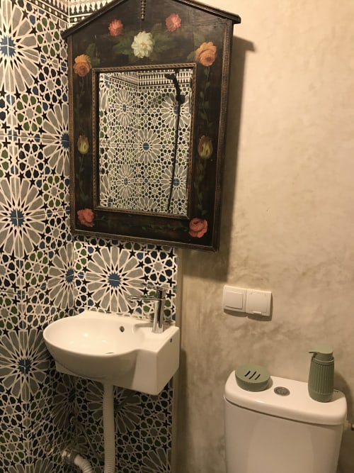 Elegant bathroom with geometric patterned tiles, ornate mirror, white sink, and toilet at Imsouane Surf Paradise hotel in