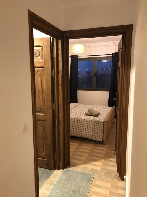 Bedroom entrance at Imsouane Surf Paradise hotel with bed, sea view windows, and wooden doors