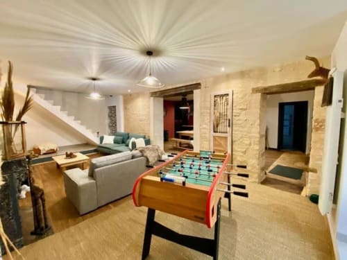 Spacious game room with foosball table, seating area, and stone walls at Vindihouses, Epinac