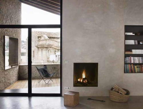 Modern cottage interior at Alemanys 5 Girona with fireplace, bookshelf, and terrace view of historic architecture