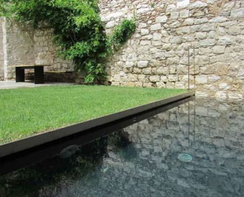 Modern courtyard at Alemanys 5 cottage in Girona with reflecting pond, green lawn, and stone walls