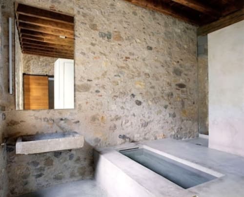 Modern bathroom in El Badiu apartment at Alemanys 5 in Girona with stone walls, sink, and built-in bathtub