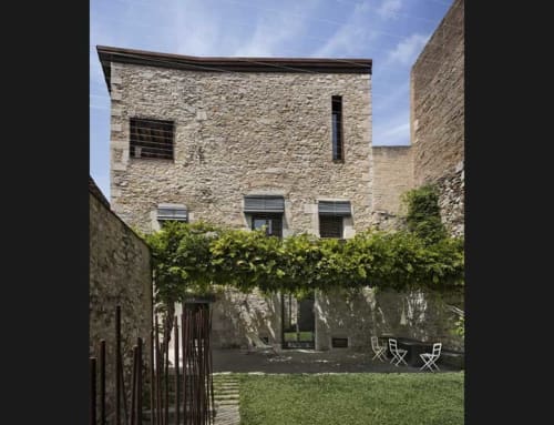 Stone courtyard at Alemanys 5 Girona BnB with ivy-covered pergola, lounge chairs, and medieval architecture