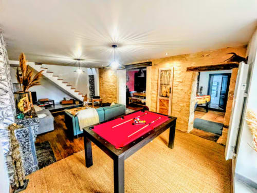 Game room with red pool table, teal sofa, and stone walls at Vindihouses Le Domaine Des Ducs in Epinac, France