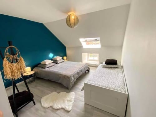 Modern bedroom at Vindihouses with teal accent wall, grey bedding, and skylight in Epinac