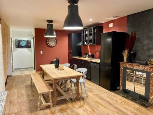 Modern kitchen-dining area at Vindihouses Le Domaine Des Ducs with red walls, black appliances, and wooden table in Epinac